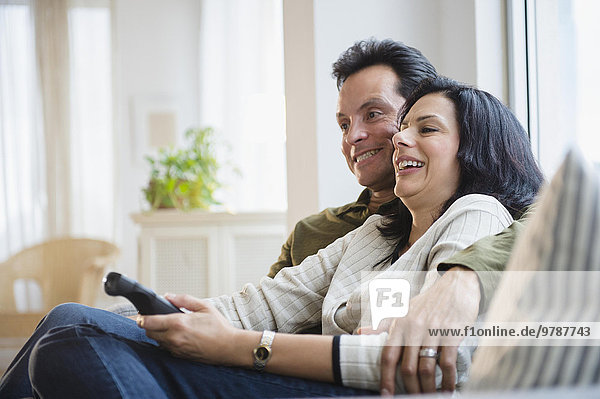 Couple watching television on sofa in living room