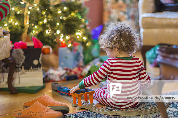 Caucasian baby boy playing with toys near Christmas tree