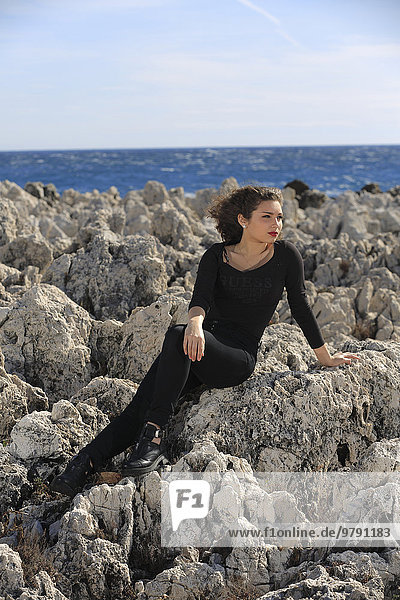 Teenager sitting on rocks by the sea  Roquebrune  Cap Martin  Côte d'Azur  France  Europe