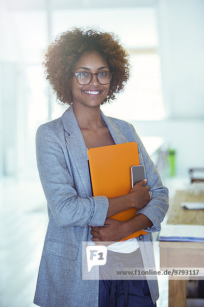 Portrait of smiling office worker holding orange file and smartphone