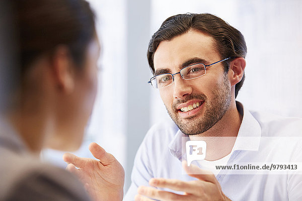 Smiling man in glasses in office with client