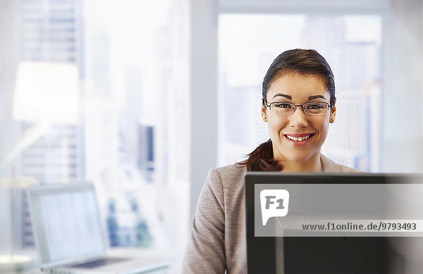 Female office worker sitting at desk using computer portrait