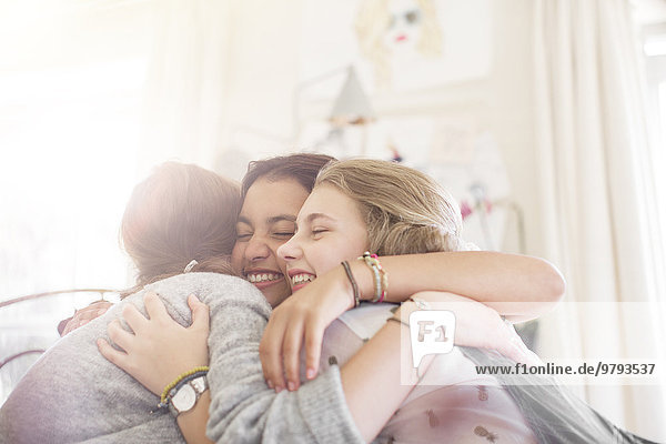 Drei Teenager-Mädchen,  die sich zu Hause umarmen