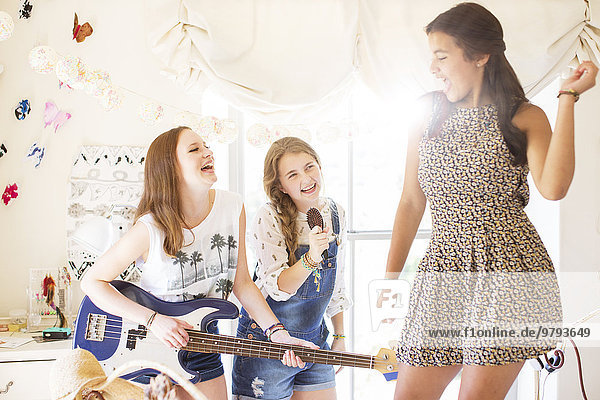 Drei Teenager-Mädchen beim Musizieren und Singen im Zimmer