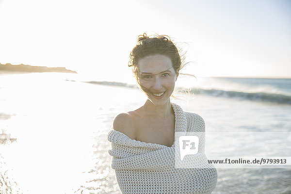Porträt einer jungen Frau in Decke gehüllt am Strand