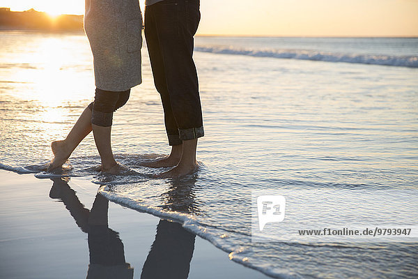 Beine eines jungen Paares am Strand stehend