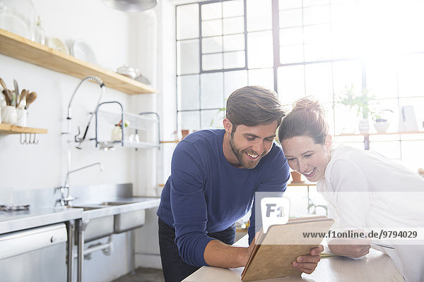 Young couple leaning at kitchen counter and looking at documents