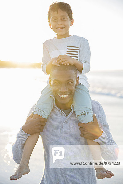 Portrait of father carrying son on shoulders and smiling