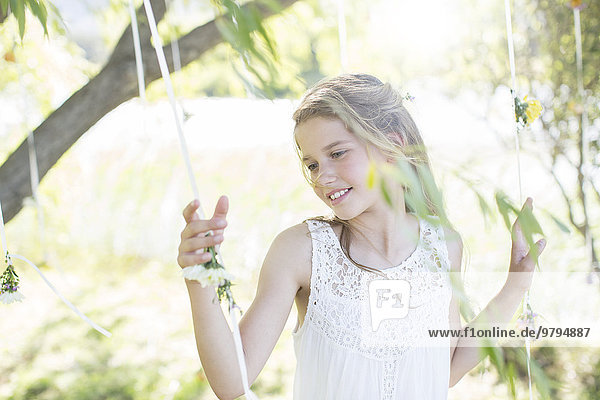 Smiling bridesmaid playing with decorations in domestic garden during wedding reception