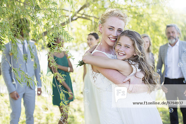 Braut umarmt Brautjungfer bei der Hochzeitsfeier im Hausgarten