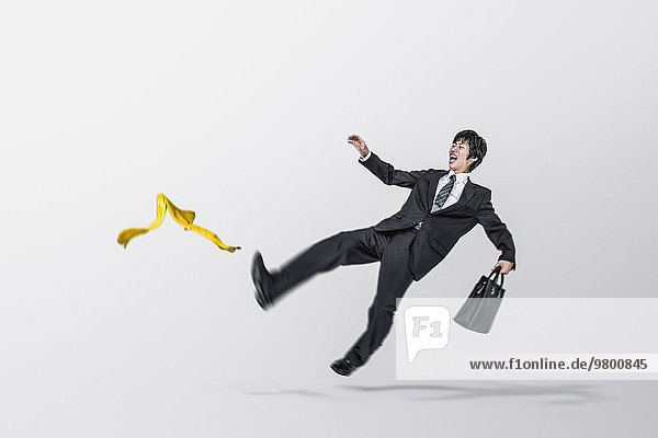 Young Japanese businessman slipping on a banana