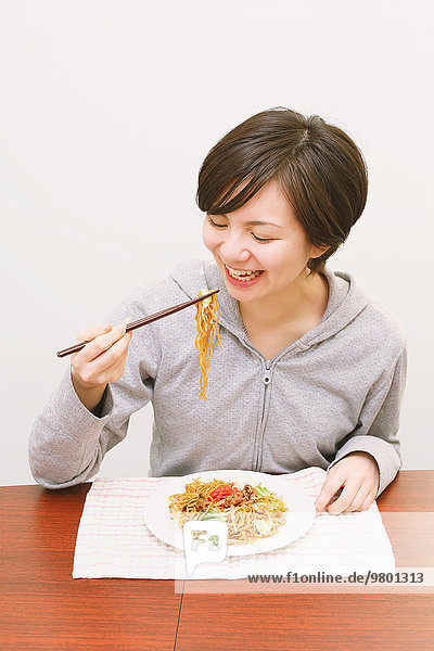 Young Japanese woman eating yakisoba noodles