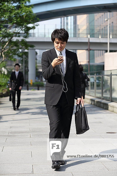 Japanese businessman walking with smartphone