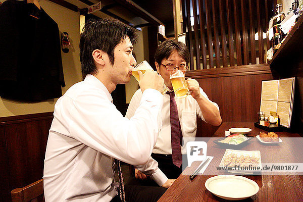 Japanese businessman drinking with his boss at a Japanese style Izakaya