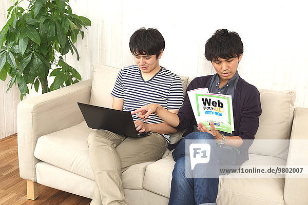 Young Japanese men working with laptop on the sofa
