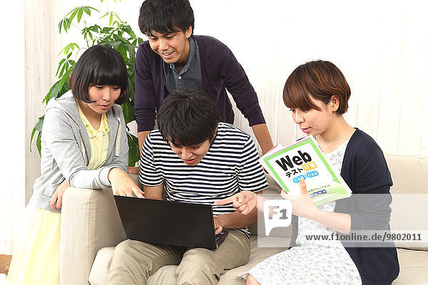 Young Japanese people working with laptop on the sofa