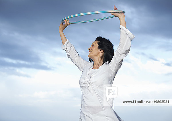 Frau hält Hula Hoop Reifen in die Luft