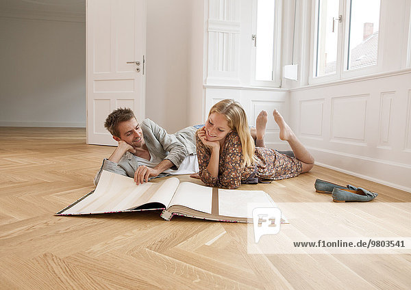 Paar mit Tapetenbuch auf dem Boden liegend