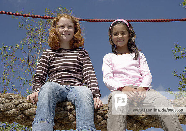 Zwei Mädchen sitzen auf einem Kletterseil
