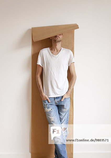 Mann mit Packpapierrolle über dem Kopf