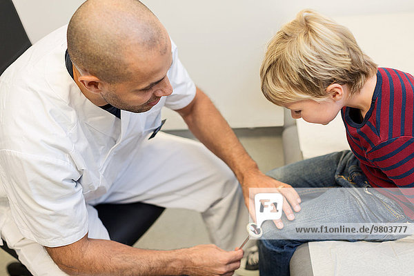 Orthopäde prüft Kniereflexe des Jungen in der Klinik