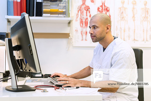 Orthopädischer Arzt mit Computer am Schreibtisch in der Klinik