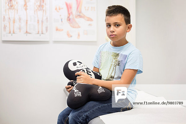 Porträt eines Jungen mit Skelettfüllung auf dem Untersuchungstisch in der orthopädischen Klinik