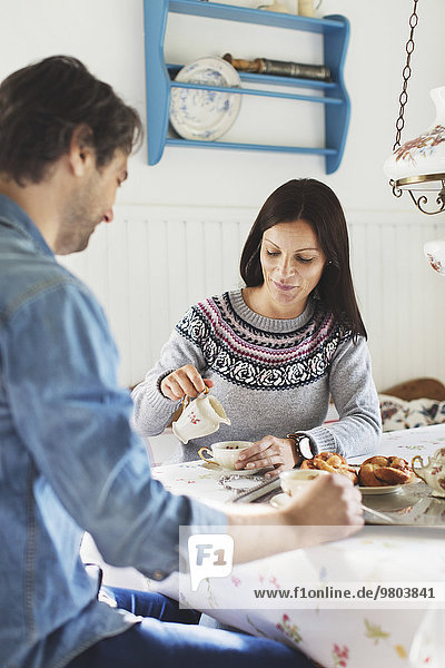 Mittlere erwachsene Frau mit Mann beim Frühstück am Tisch