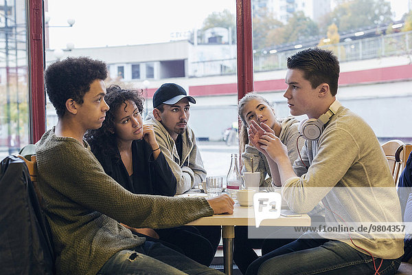 University students communicating at table in cafeteria