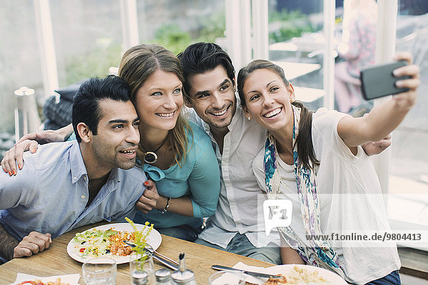 Smiling business couples taking selfie in cafe