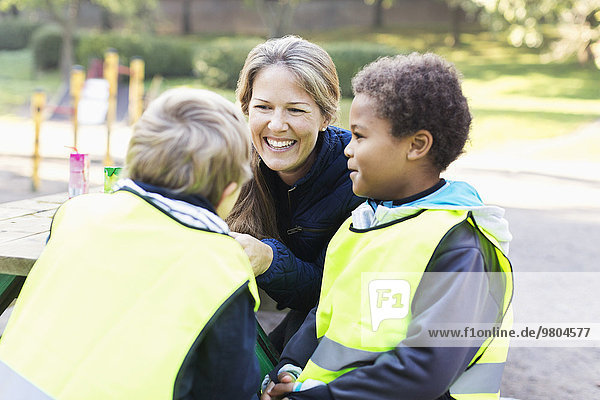 Glückliche Lehrerin mit Kindern in reflektierender Jacke