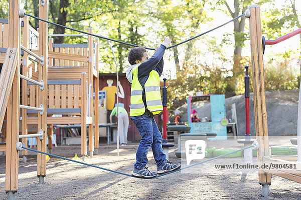 Side view of boy balancing on rope at playground
