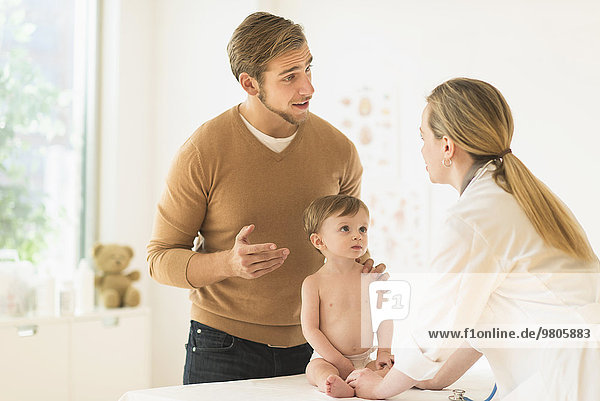 Small boy (2-3) with his father and female doctor in doctor's office