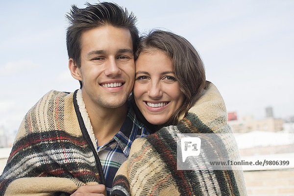 Portrait of young couple wrapped in blanket