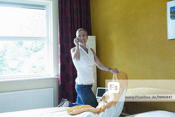 Netherlands  Goirle  Mid-adult woman making bed and talking on phone