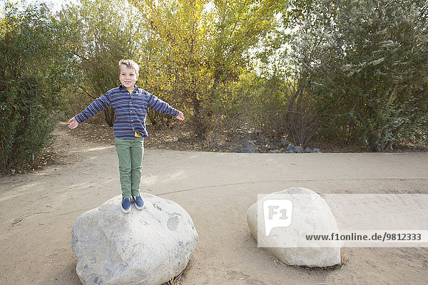 Porträt eines Jungen auf einem Felsblock im Park