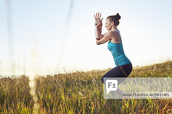 Reife Frau beim Yoga auf dem Feld