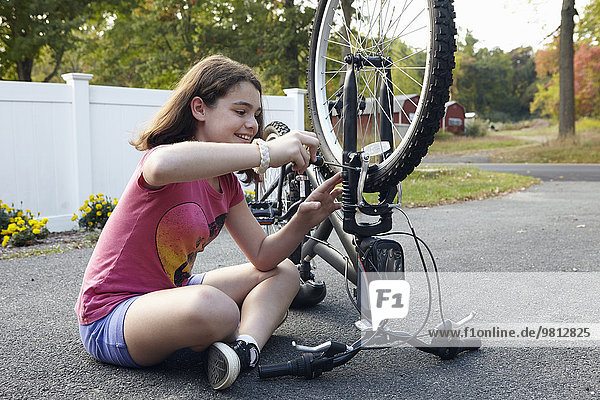 Mädchen reparieren Fahrrad auf der Einfahrt