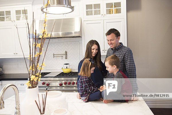Paar und zwei Kinder beim Plaudern in der Küche