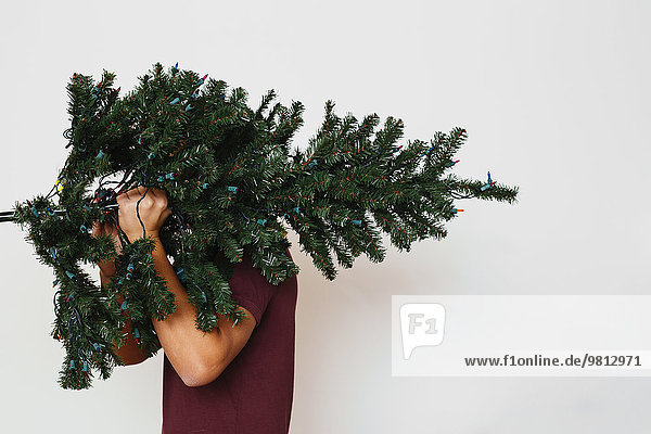 Mann mit künstlichem Weihnachtsbaum