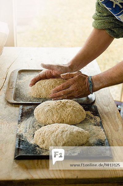 Der reife Mann  der Bio-Brot herstellt  konzentriert sich auf Hände und Brot.