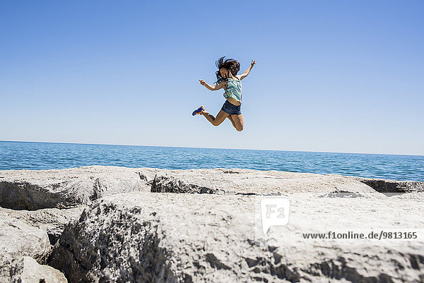 Junge Frau beim Springen über Felsen  Scarborough Bluffs  Toronto  Ontario  Kanada