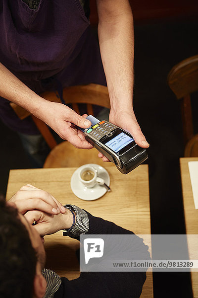 Man paying his bill in restaurant  using credit card  elevated view