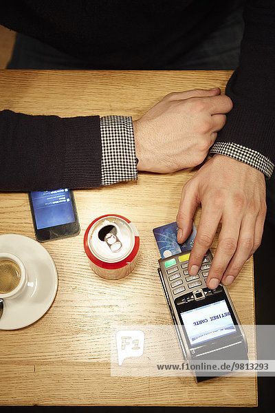 Kunde im Restaurant gibt PIN-Nummer in Kreditkartenleser ein