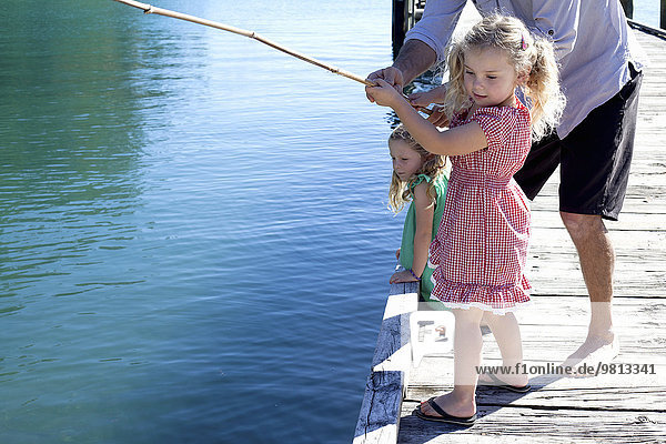 Erwachsener Mann und Tochter beim Fischen vom Pier,  Neuseeland