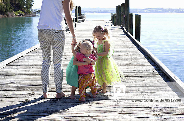 Mittlere erwachsene Frau und drei Mädchen am Pier,  Neuseeland