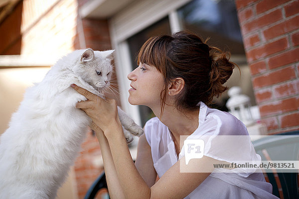 Mittlere erwachsene Frau mit zögerlicher Katze vor der Haustür