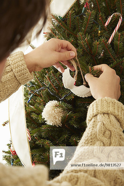 Close up of young man putting decorations on christmas tree