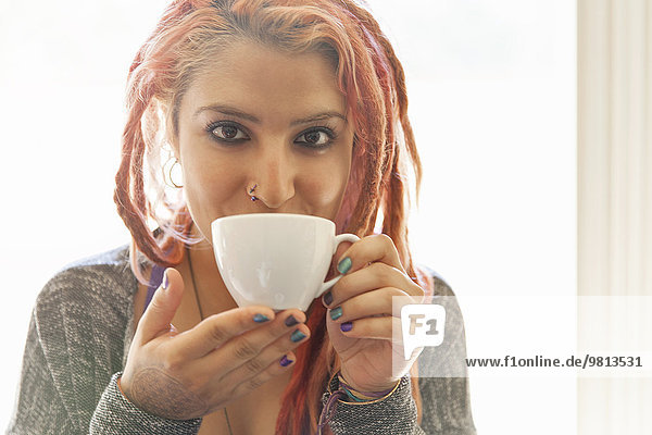 Young woman with pink dreadlocks drinking herbal tea