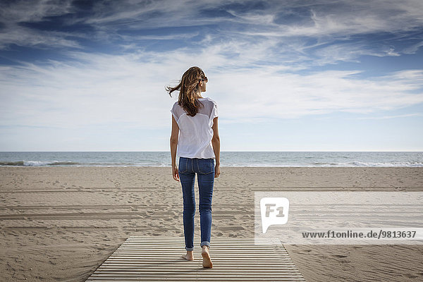 Rückansicht der mittleren erwachsenen Frau beim Bummeln am Strand  Castelldefels  Katalonien  Spanien